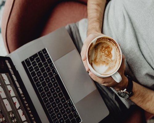 Man working comfortably on laptop while drinking coffee in Lisbon